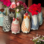 Single blue and white striped cat bud vase holding small white flowers