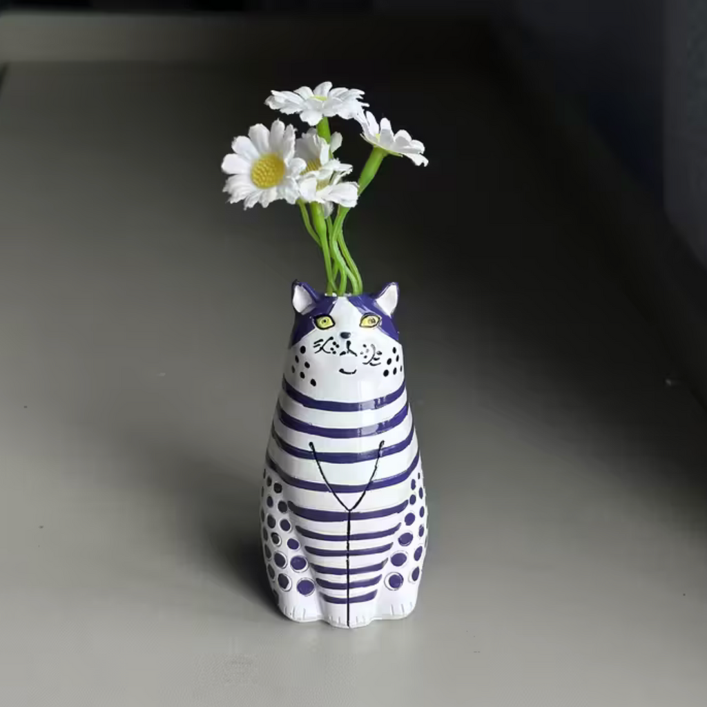 Close-up of a red and white striped cat-shaped bud vase held in a hand
