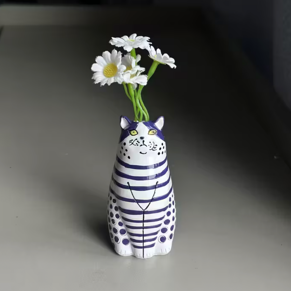 Close-up of a red and white striped cat-shaped bud vase held in a hand