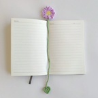 A selection of six colourful crochet flower bookmarks arranged beside a book