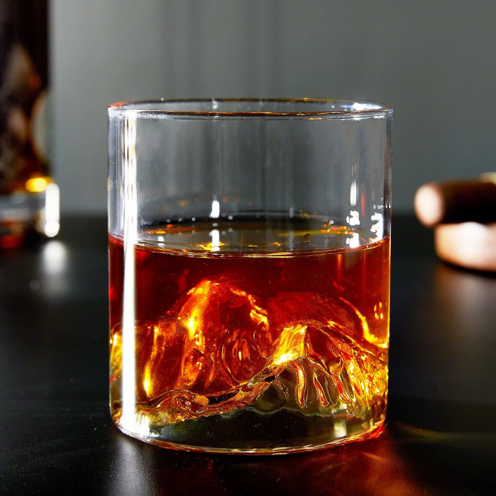 Mountain whisky glass filled with amber whisky on a dark drinks table