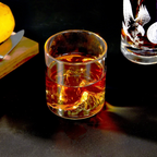 Whisky being poured into a mountain-inspired tumbler beside another glass