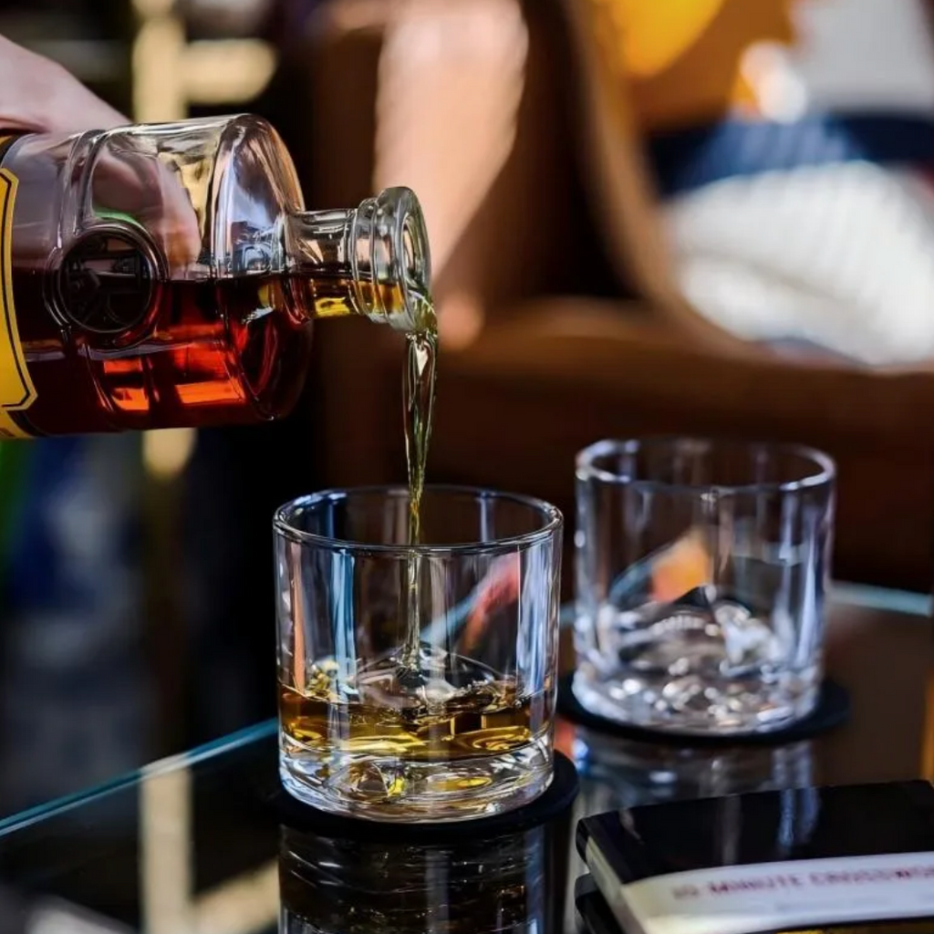 Hand holding a square mountain whisky glass filled with whisky and ice
