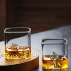 Large and small mountain whisky glasses filled with amber whisky and ice