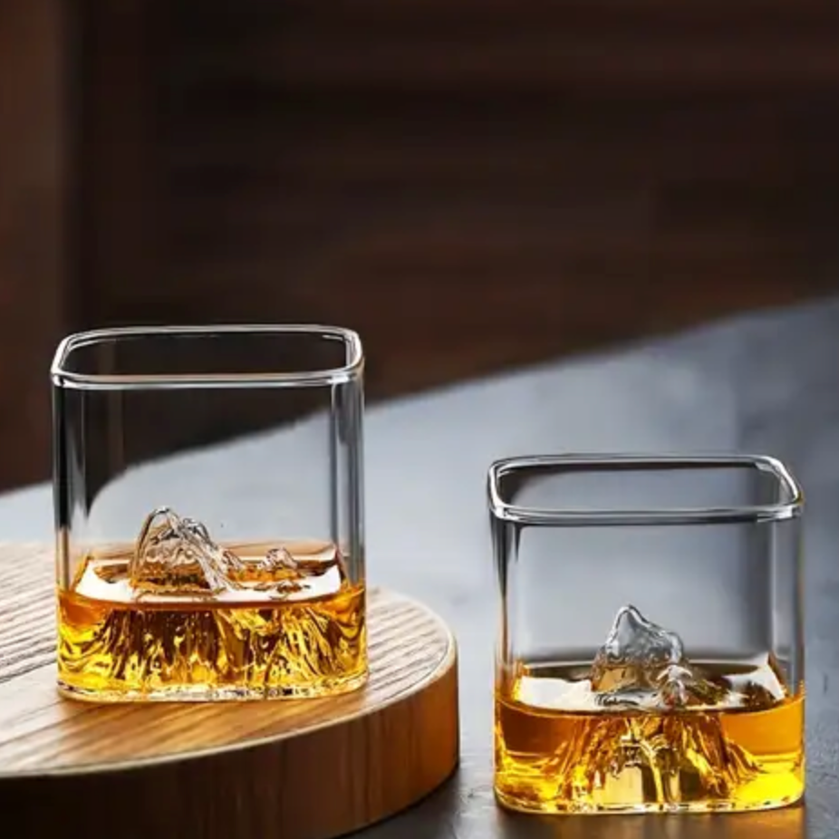 Large and small mountain whisky glasses filled with amber whisky and ice