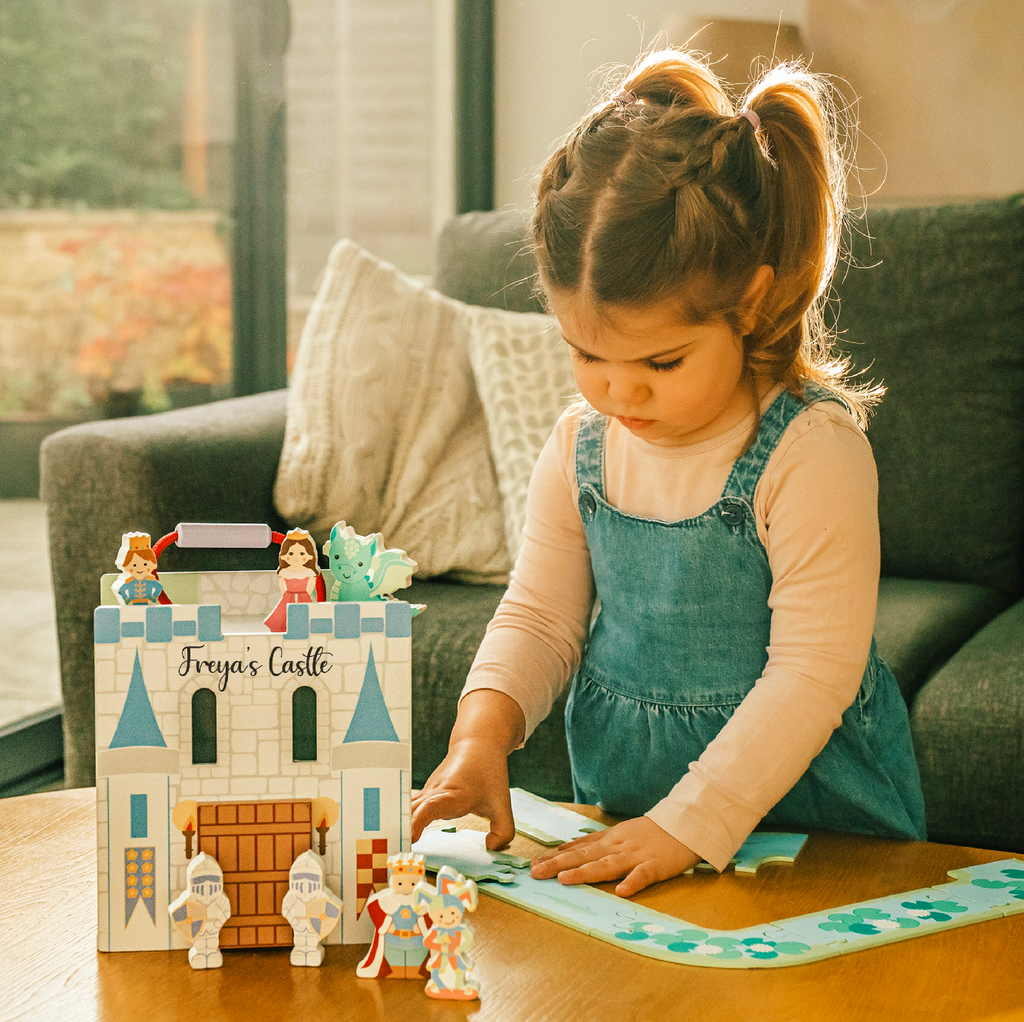 Child playing with a personalised wooden castle labelled Freya's Castle