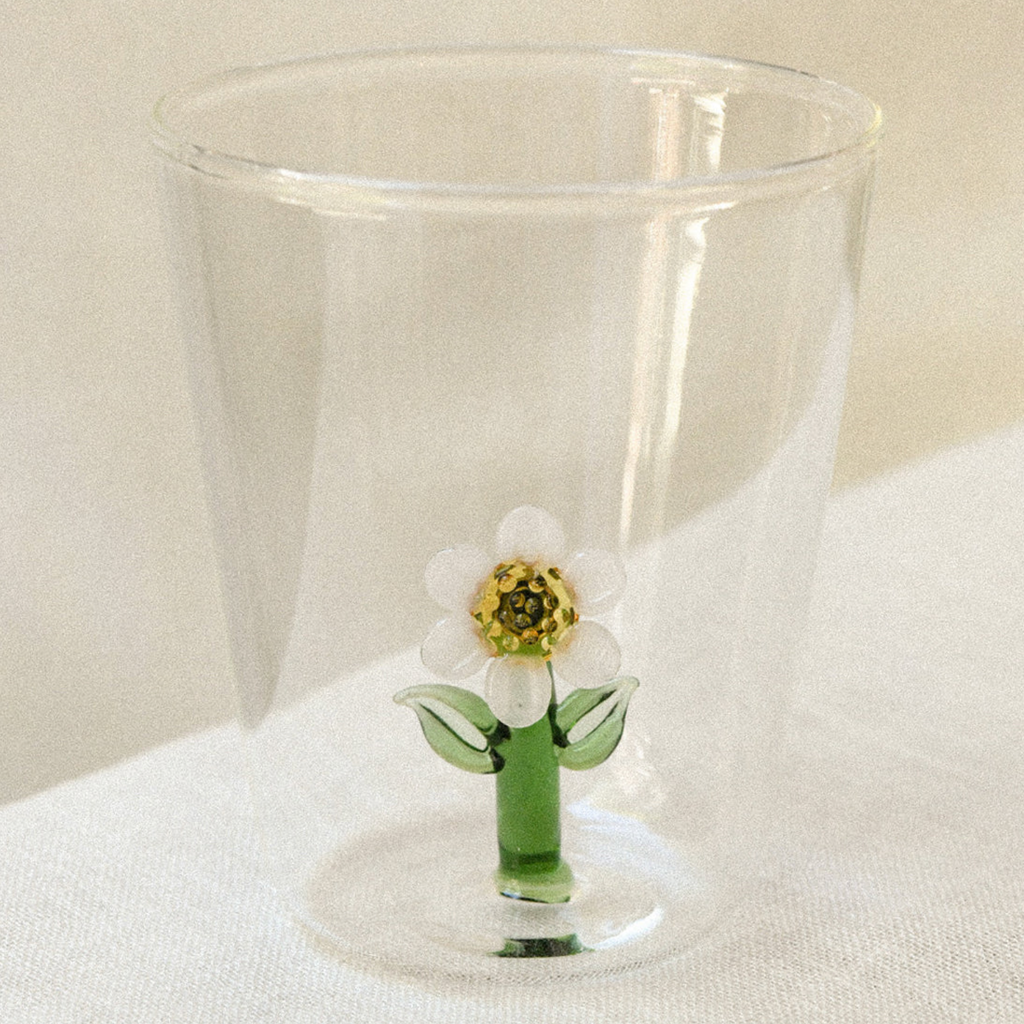 Two clear glass tumblers with a glass flower inside, on a wooden garden table