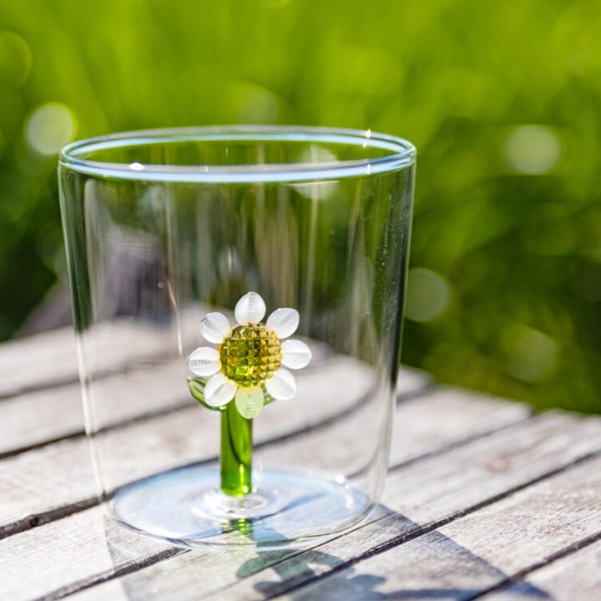 Water being poured into the sunflower glass tumbler outdoors