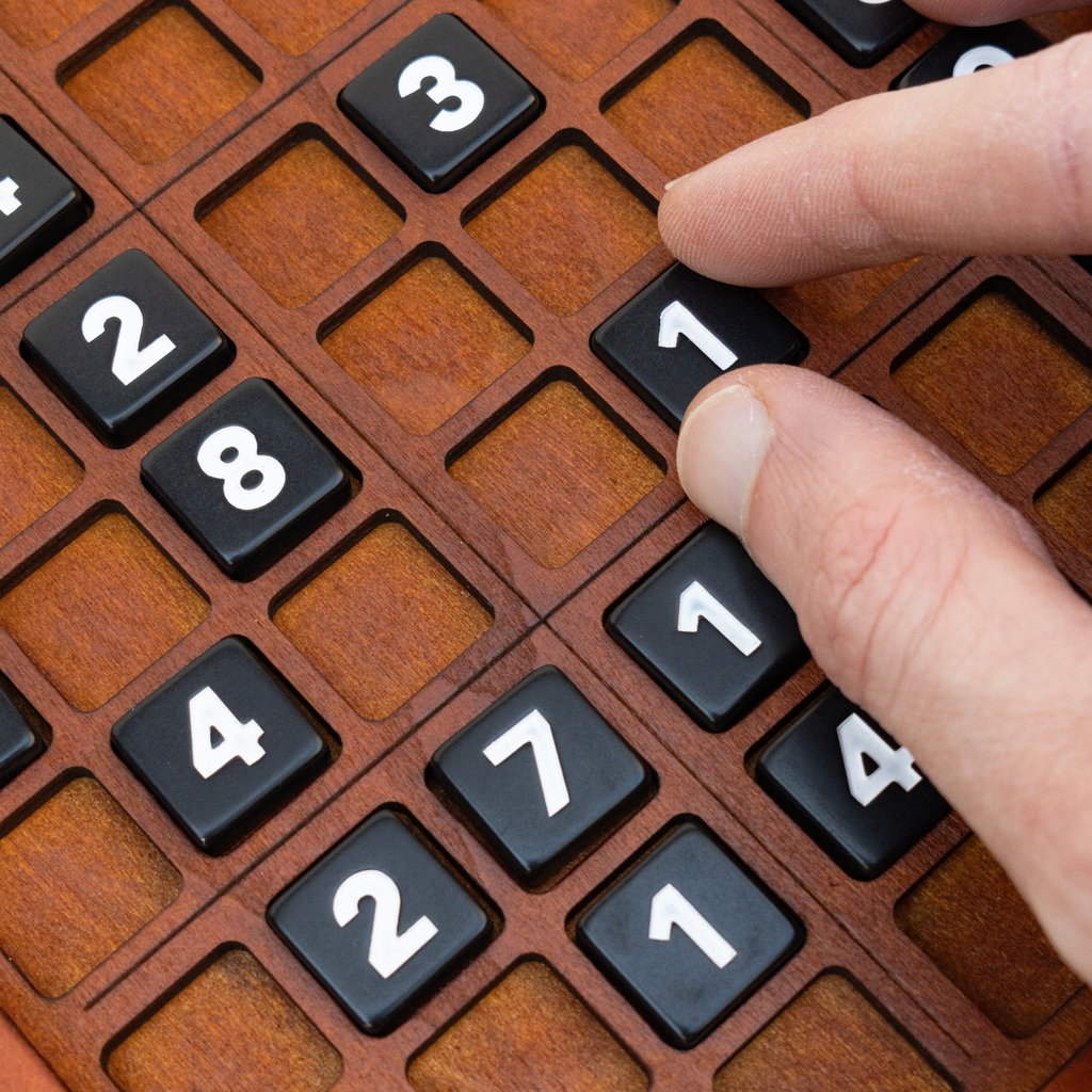 Close-up of black numbered tiles on a personalised wooden Sudoku board