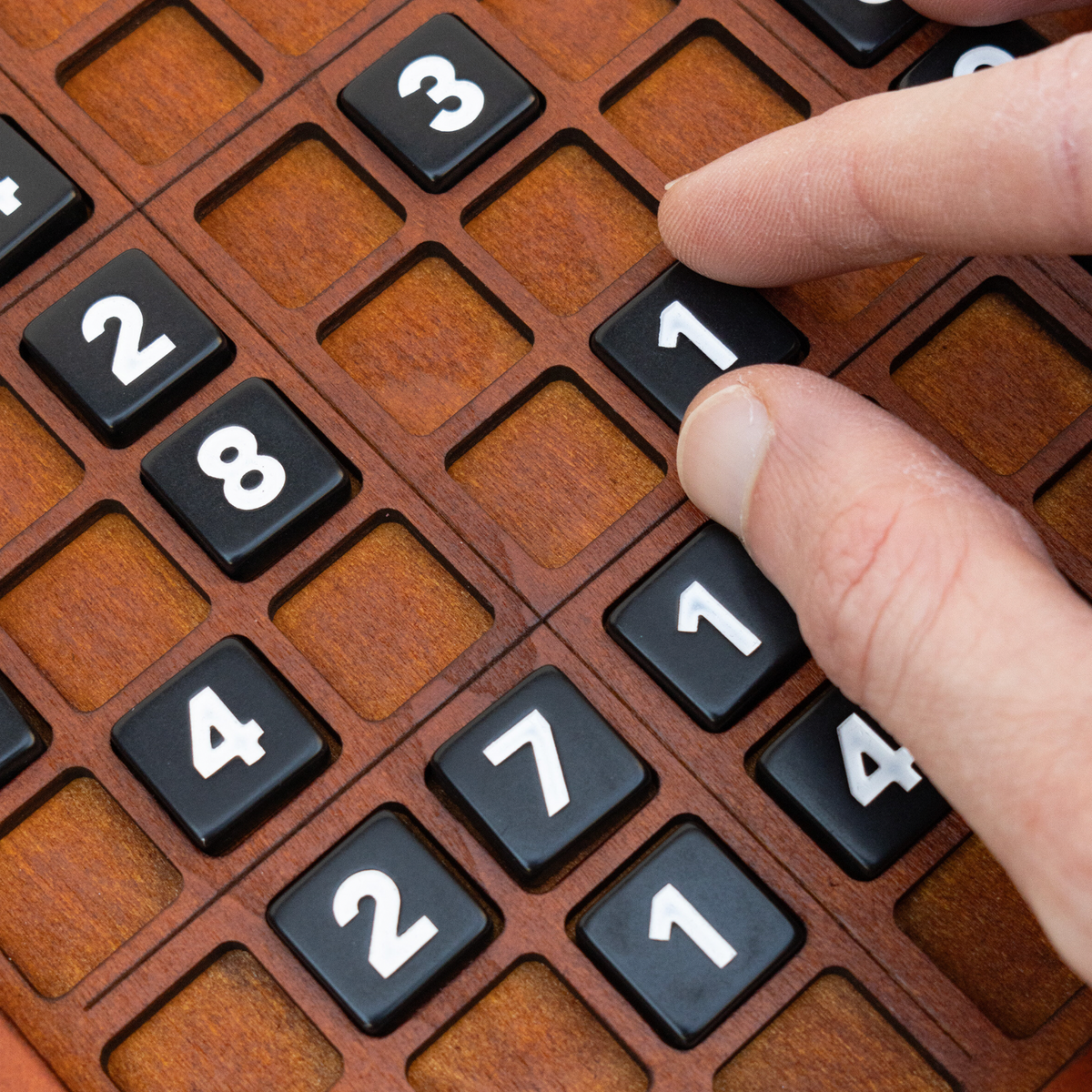 Close-up of black numbered tiles on a personalised wooden Sudoku board