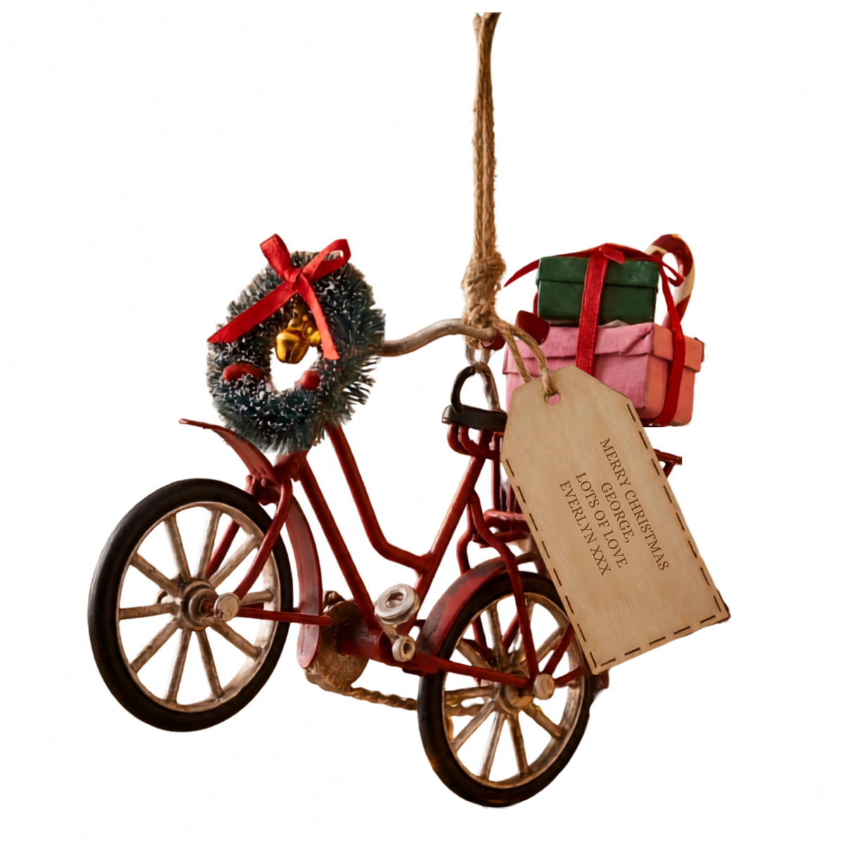 A decorative hanging ornament shaped like a red bicycle with a tinsel wreath, red ribbon, small gift boxes, and a wooden tag that reads 'MERRY CHRISTMAS LOVE TO ALL' on a white background.