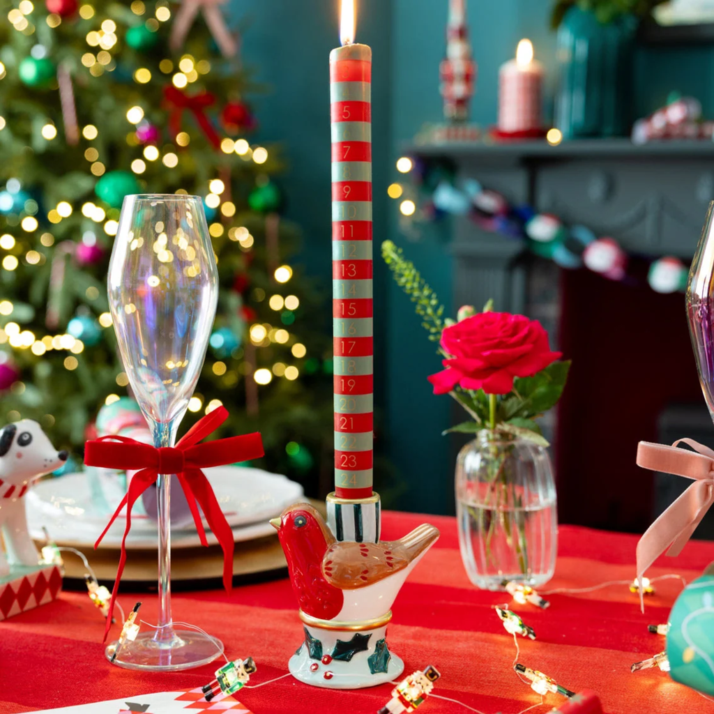 Decorative Christmas table setting with candles, glasses, and a rose.