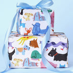 Two wrapped gift boxes stacked together with a light blue satin ribbon, featuring a colorful cartoon animal print on a white background, set against a solid light blue backdrop.