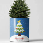A small artificial Christmas tree in a cylindrical blue tin can with a festive 'Merry Christmas' holiday print, set against a plain light gray background.