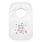 A white baby bib with a personalized Christmas print reading 'Amelia's First Christmas 2026' in red, surrounded by small festive illustrations, shown on a plain white background.