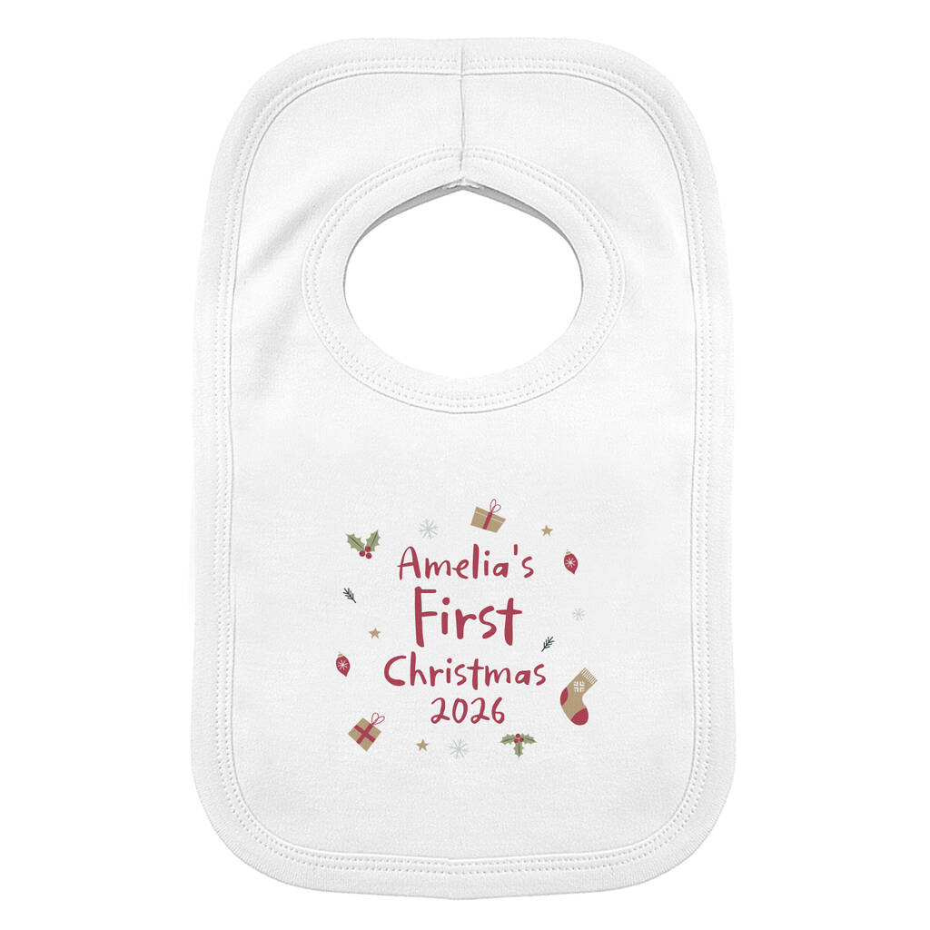 A white baby bib with a personalized Christmas print reading 'Amelia's First Christmas 2026' in red, surrounded by small festive illustrations, shown on a plain white background.