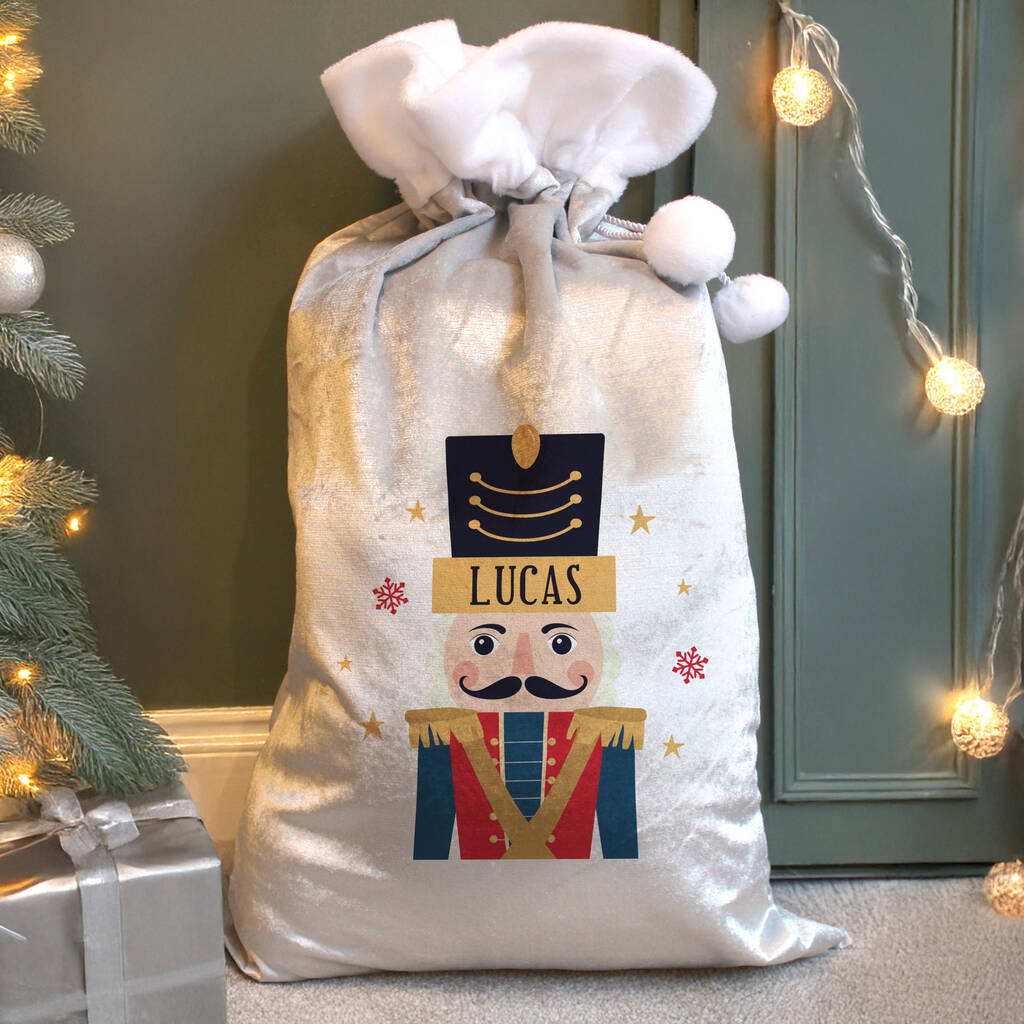 Personalized Christmas sack with a nutcracker design and the name 'Lucas', placed against a festive background with lights and a tree.