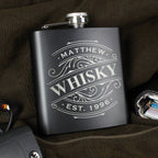 Black whiskey flask with 'Matthew Whisky' engraving on a dark surface